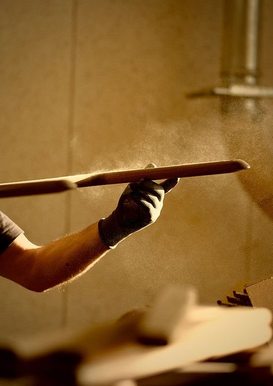 A craftsperson spray-finishing a timber panel